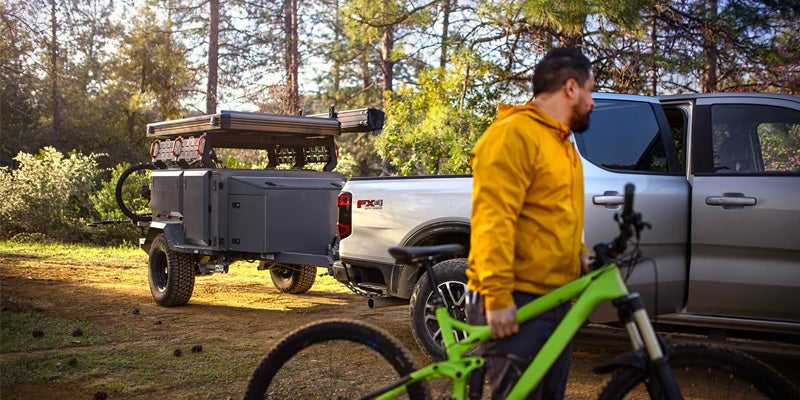 2024 ford ranger with trailer attached parked with right hand back door open with man in yellow hoodie holding green bicycle